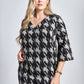 Woman wearing an above the knee fuller bust houndstooth v-neck shift dress with french darts, flared sleeves and pockets designed by Miriam Baker.