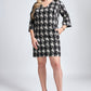 Woman wearing an above the knee fuller bust houndstooth v-neck shift dress with flared sleeves and pockets designed by Miriam Baker.