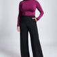 Front view of a size 12 woman wearing a fuller bust mock neck pullover in violet paired with black high waisted wide leg trousers featuring in-seam pockets.