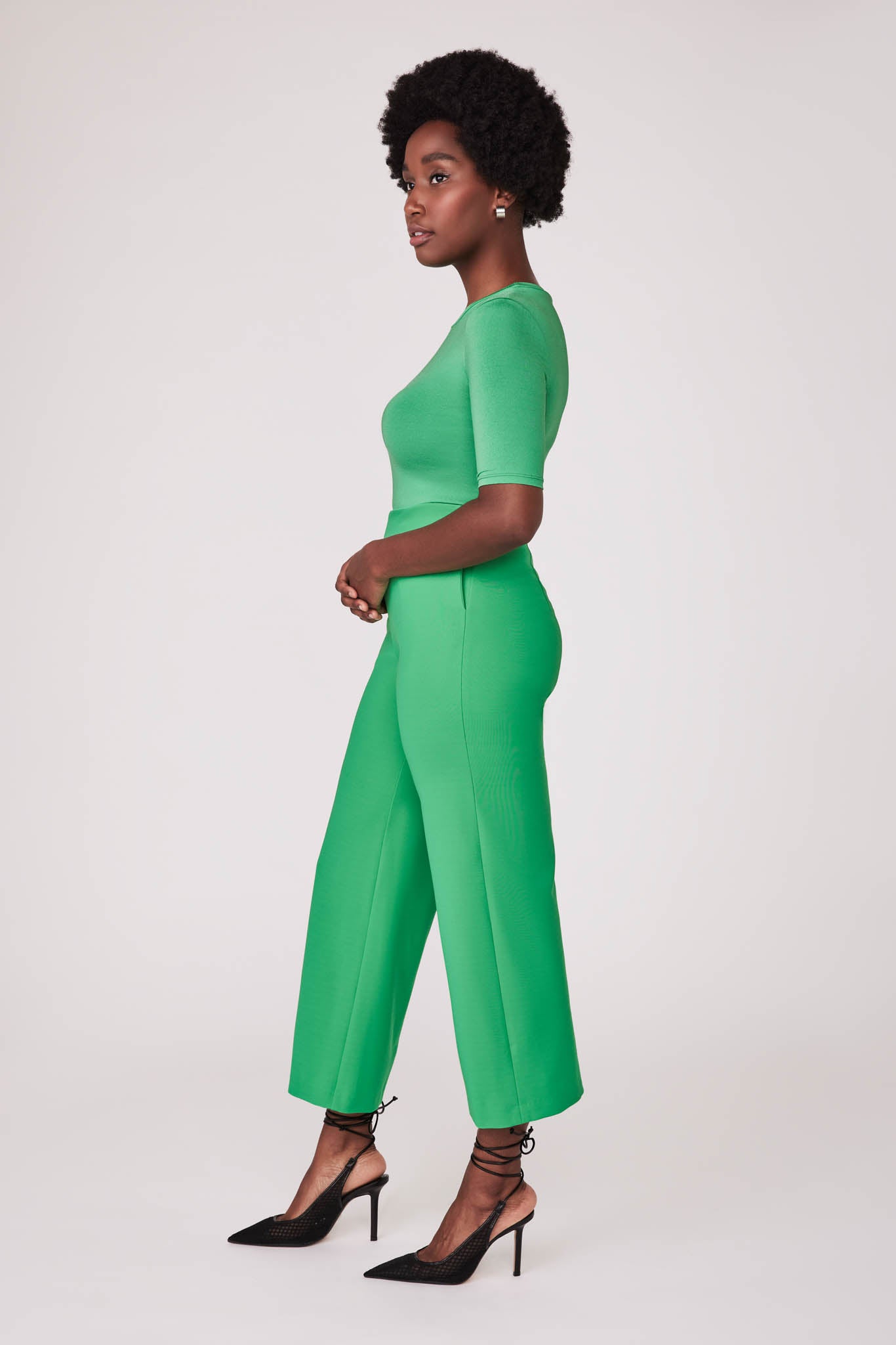Side view of a woman wearing a half sleeve crew neck fuller bust T-shirt paired with matching wide leg cropped pants in vibrant kiwi green by Miriam Baker.