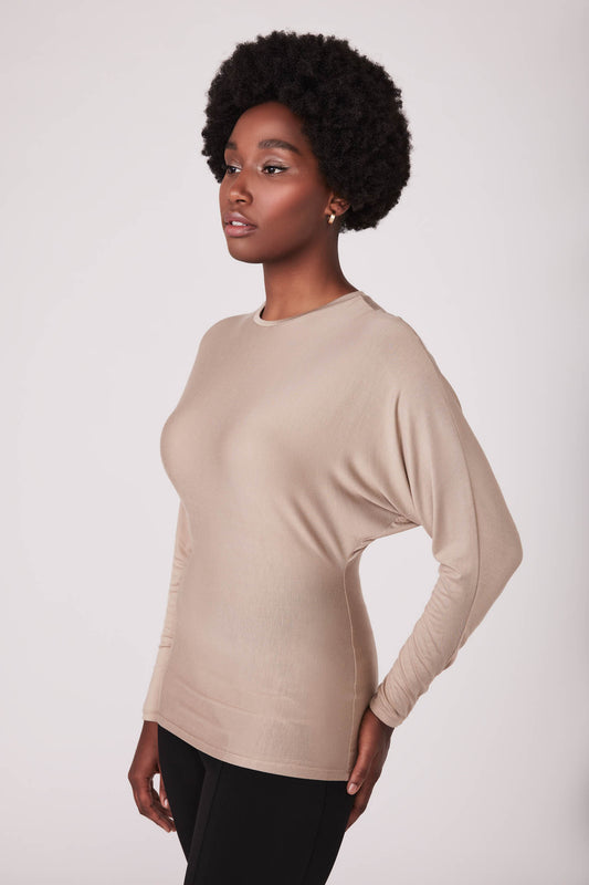 Side view of woman wearing a dolman sleeve batwing pullover in beige micromodal by Miriam Baker.