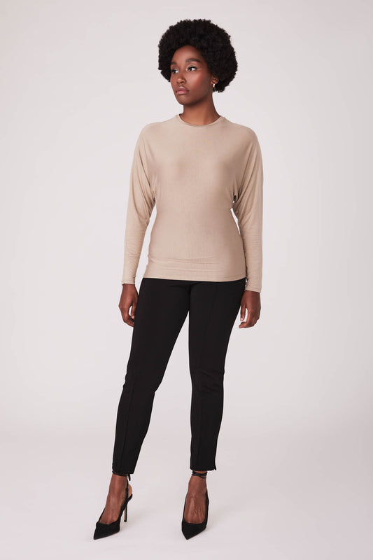 Front view of woman wearing a dolman sleeve batwing pullover in beige micromodal paired with a stretch viscose cigarette pant by Miriam Baker.
