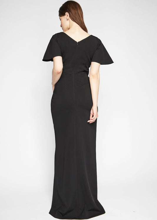 Back view of a woman wearing a fuller bust stretch jersey black evening gown with a plunging neckline designed by Miriam Baker.