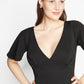Front detailed view of a woman wearing a fuller bust stretch jersey black evening gown with a plunging neckline designed by Miriam Baker.