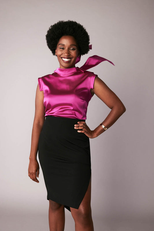 Front view of a woman wearing a fuchsia stretch silk charmeuse fuller bust blouse with bust darts and pussy bow collar designed by Miriam Baker.