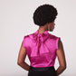 Back view of a woman wearing a fuchsia stretch silk charmeuse fuller bust blouse with bust darts and pussy bow collar designed by Miriam Baker.