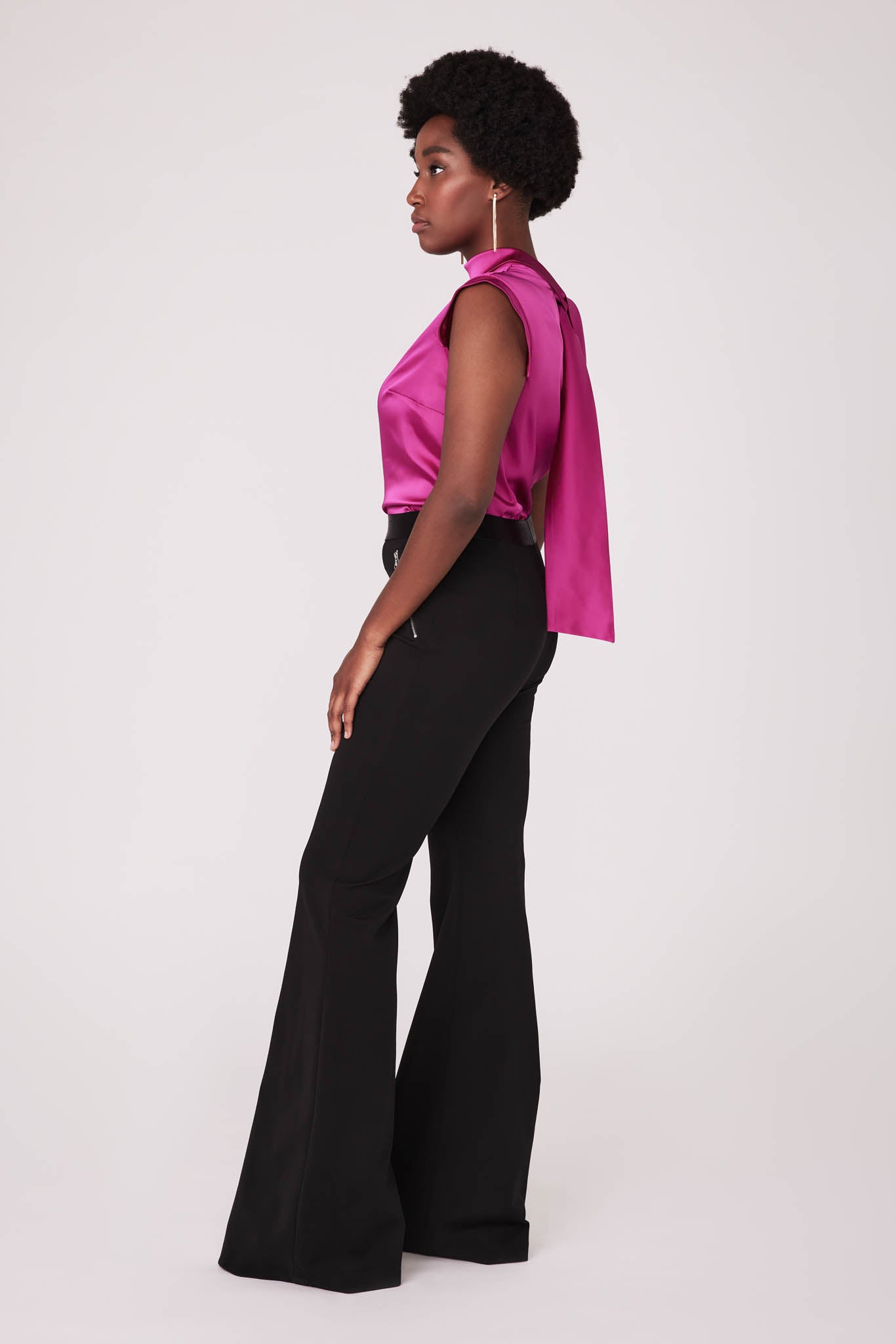 Side view of a woman wearing a fuchsia stretch silk charmeuse fuller bust blouse with bust darts and pussy bow collar designed by Miriam Baker.