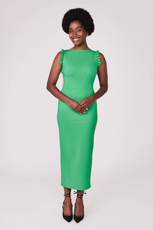 Front view of a woman wearing a green stretch viscose fuller bust midi length bodycon dress with shoulder ruffles and a back slit designed by Miriam Baker.