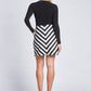 Back view of a woman wearing a black pullover tucked into a black and white chevron stripe A-line mini skirt with side seam pockets designed by Miriam Baker.