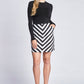 Front view of a woman wearing a black pullover tucked into a black and white chevron stripe A-line mini skirt with side seam pockets designed by Miriam Baker.