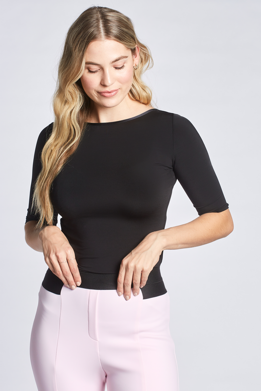 Front view of a woman wearing a black stretch viscose DD+ half sleeve boatneck pullover with back ballerina scoop neckline designed by Miriam Baker.