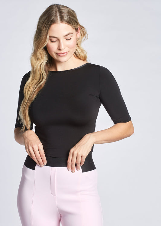 Front view of a woman wearing a black stretch viscose half sleeve boatneck pullover with back ballerina scoop neckline designed by Miriam Baker.