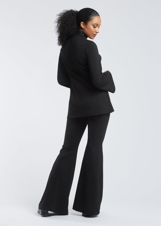 Back view of a woman wearing a black fuller bust tunic style top with flared sleeves in stretch crepe fabric designed by Miriam Baker.