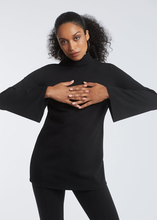 Woman wearing a black fuller bust tunic style top with flared sleeves in stretch crepe fabric designed by Miriam Baker.