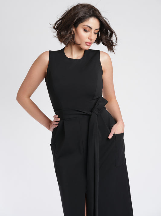 Size 6 woman wearing a luxury fuller bust stretch viscose evening dress with oversized patch pockets and waist sash detail by Miriam Baker.