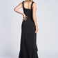 Back view of a woman wearing a black stretch viscose fuller bust empire waist gown with high low flounce hem and shoulder bow detail designed by Miriam Baker.