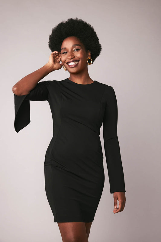 Woman wearing a black stretch viscose fuller bust princess line split sleeve bodycon dress with a crew neck and invisible zipper designed by Miriam Baker.