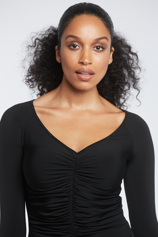 Woman wearing a black stretch viscose jersey v-neck long sleeve fuller bust pullover with front ruching designed by Miriam Baker.