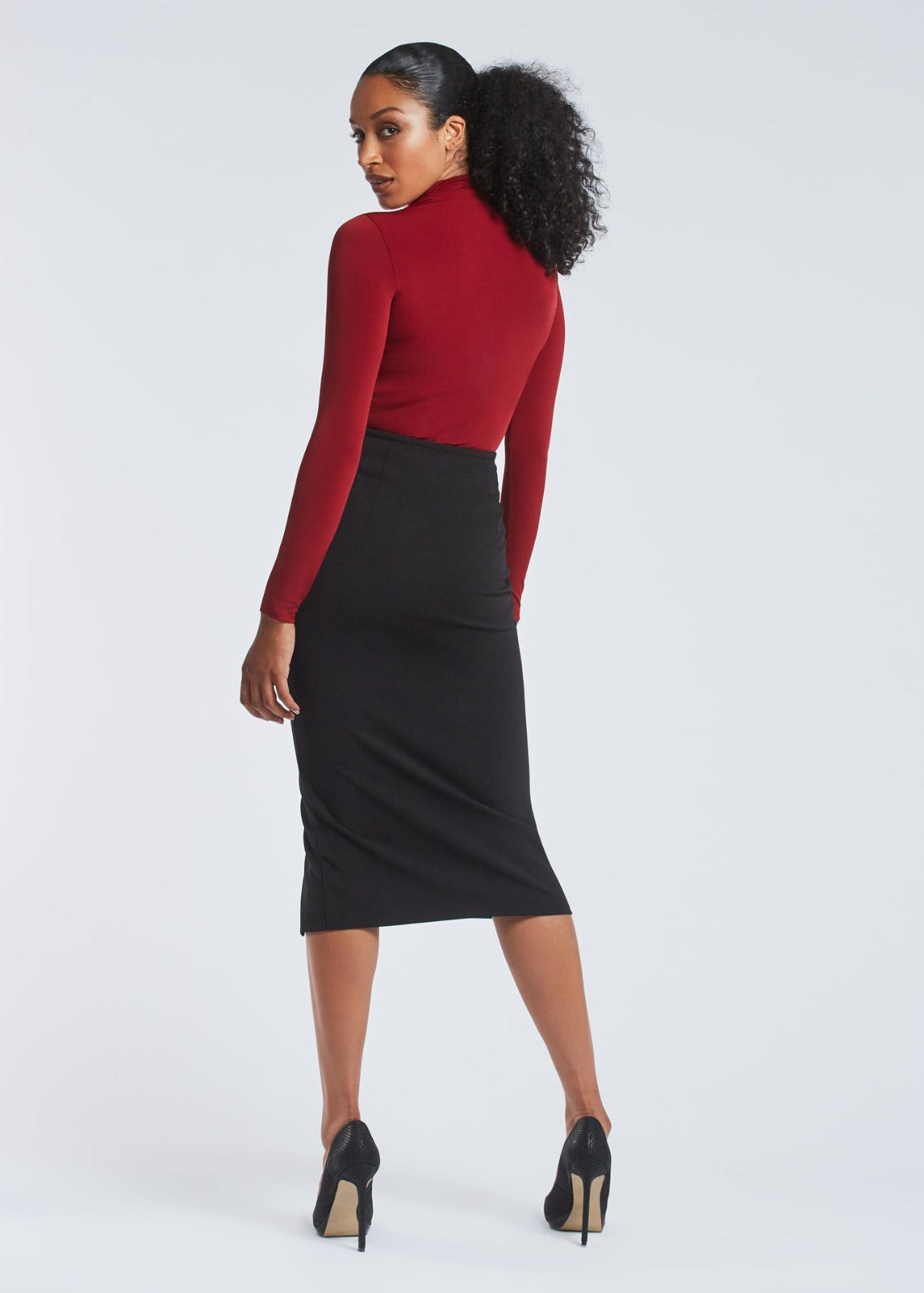 Back view of a woman wearing a red stretch viscose fuller bust long sleeve mock neck pullover by Miriam Baker.