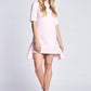 Woman wearing a pale pink half sleeve crew neck fuller bust t-shirt dress with high low ruffle hem designed by Miriam Baker.