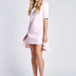 Woman wearing a pale pink half sleeve crew neck fuller bust t-shirt dress with high low ruffle hem designed by Miriam Baker.