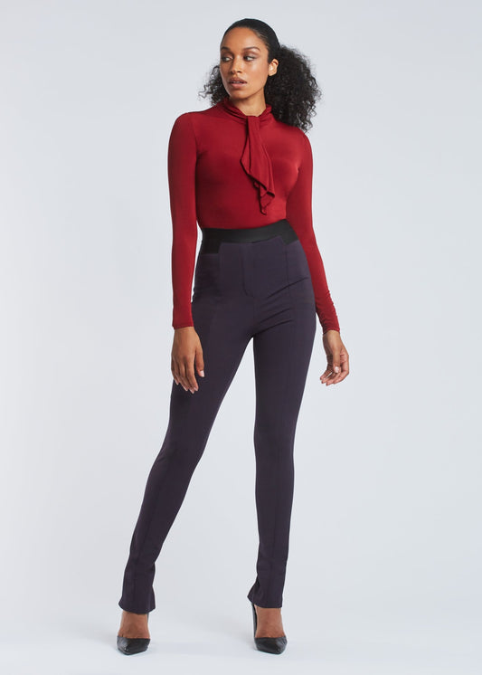 Front view of a woman wearing high waisted full length stretch trousers in navy blue with an exposed zipper at the hem designed by Miriam Baker.