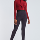 Front view of a woman wearing high waisted full length stretch trousers in navy blue with an exposed zipper at the hem designed by Miriam Baker.