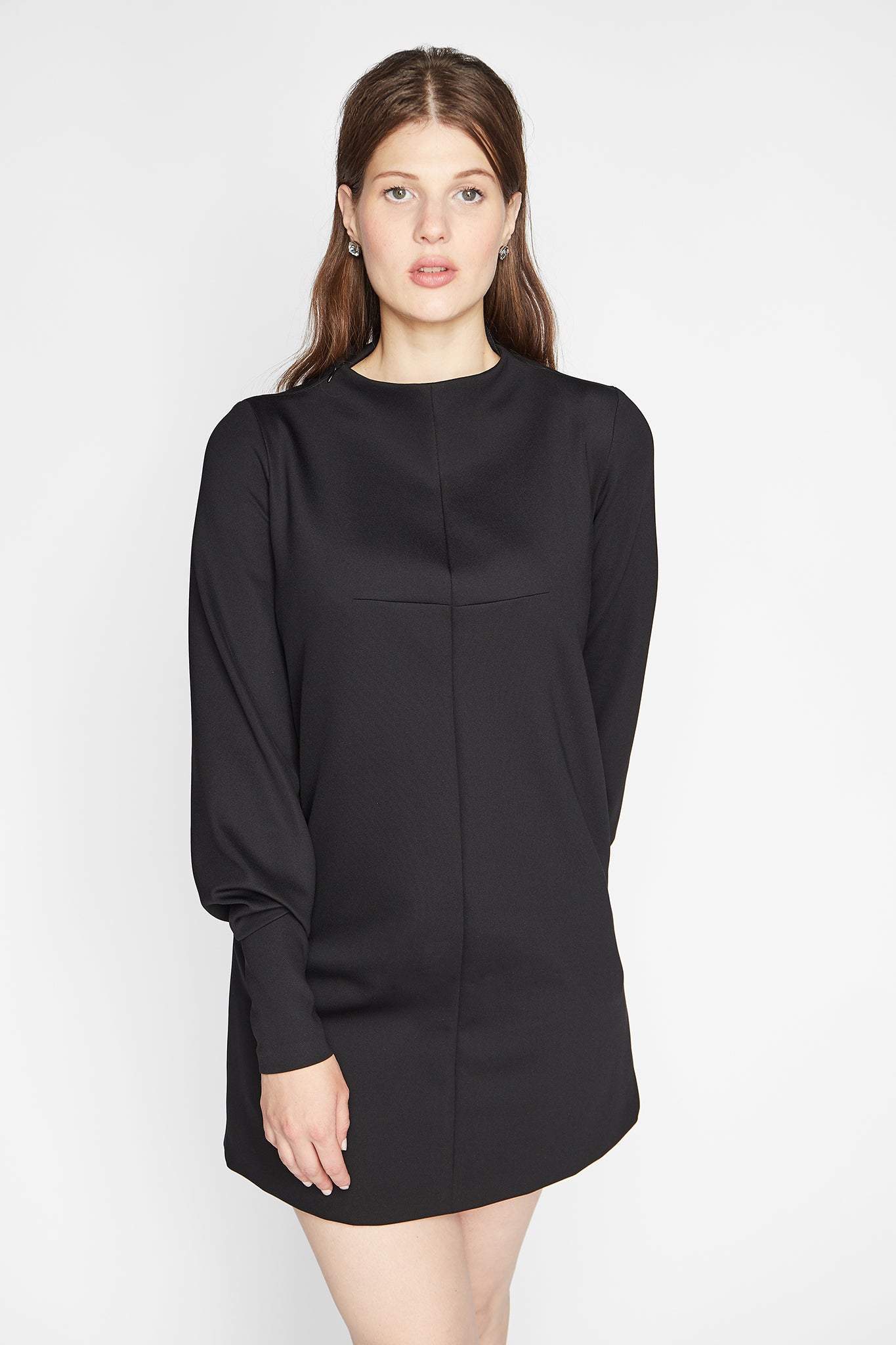 Woman wearing a long sleeve fuller bust mock neck shift dress with pockets in black stretch jersey designed by Miriam Baker.