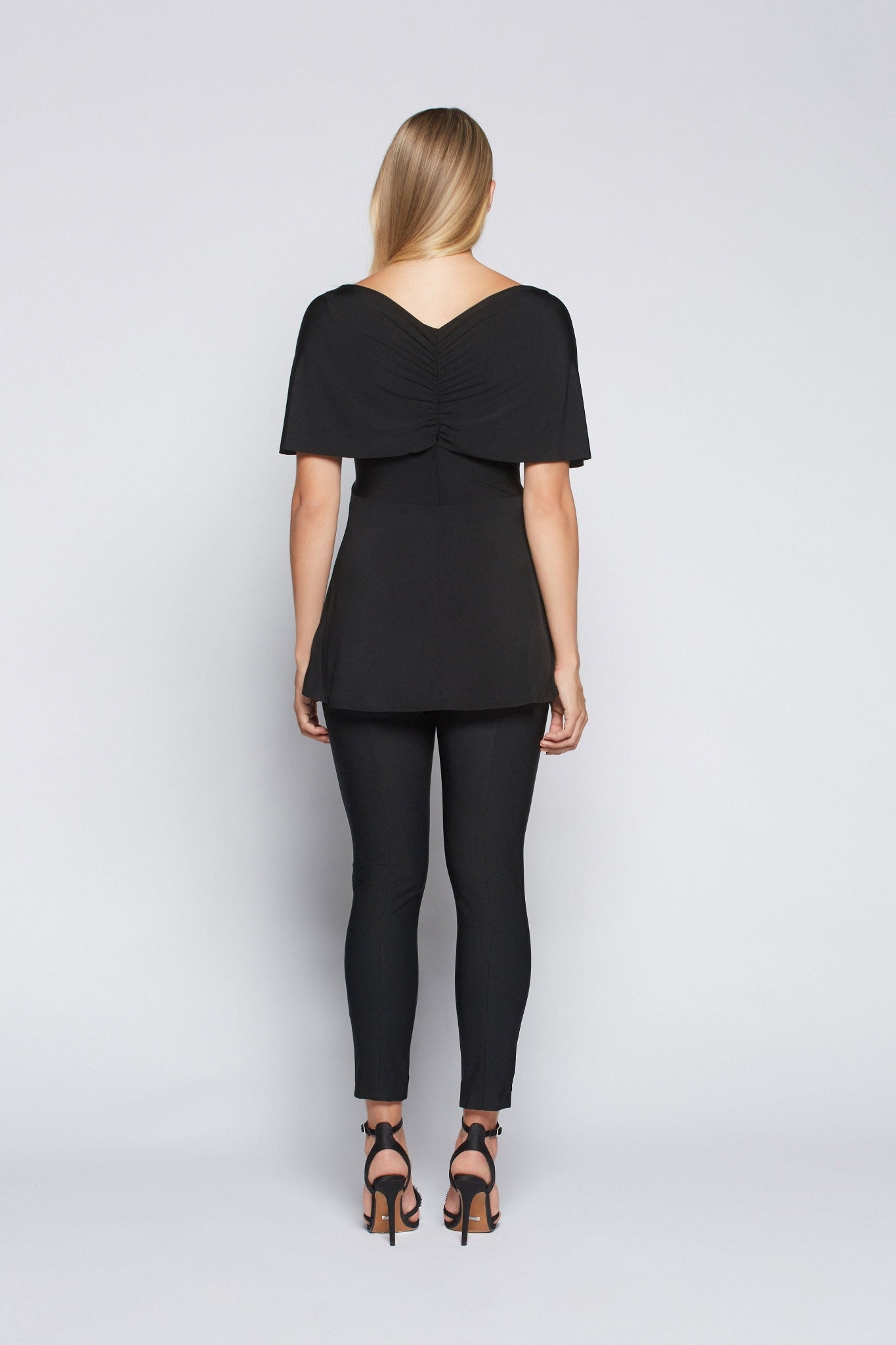 Back view of a woman wearing a fuller bust low cut v-neck top with a butterfly twist detail at the empire waist in black stretch viscose jersey by Miriam Baker.