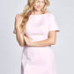 Front view of a woman wearing a pale pink fuller bust mini dress with stretch featuring a boatneck and short sleeves designed by Miriam Baker and made in Canada. 