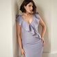 Woman wearing a stretch viscose fuller bust v-neck sheath dress with ruffles that frame the neckline in lilac designed by Miriam Baker.