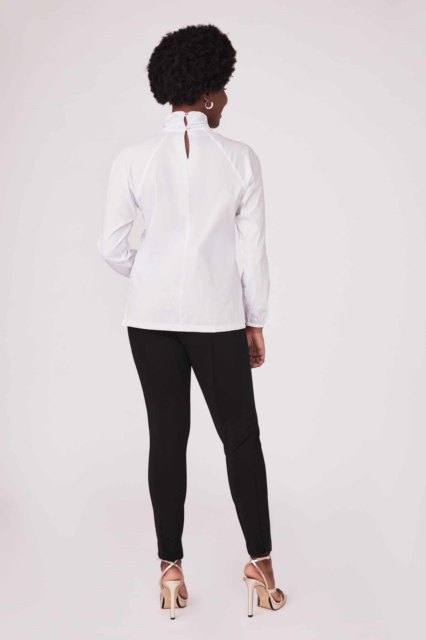 Back view of a woman wearing a white stretch cotton fuller bust blouse with front cut out detail and twist collar by Miriam Baker.