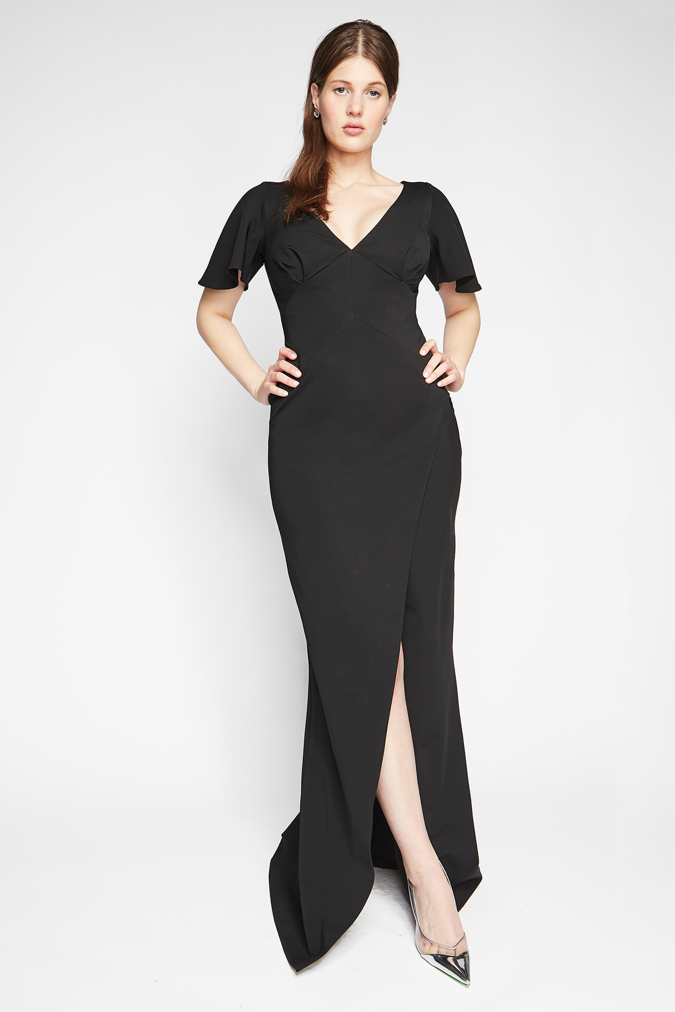 Front view of a woman wearing a fuller bust stretch jersey black evening gown with a plunging neckline designed by Miriam Baker.
