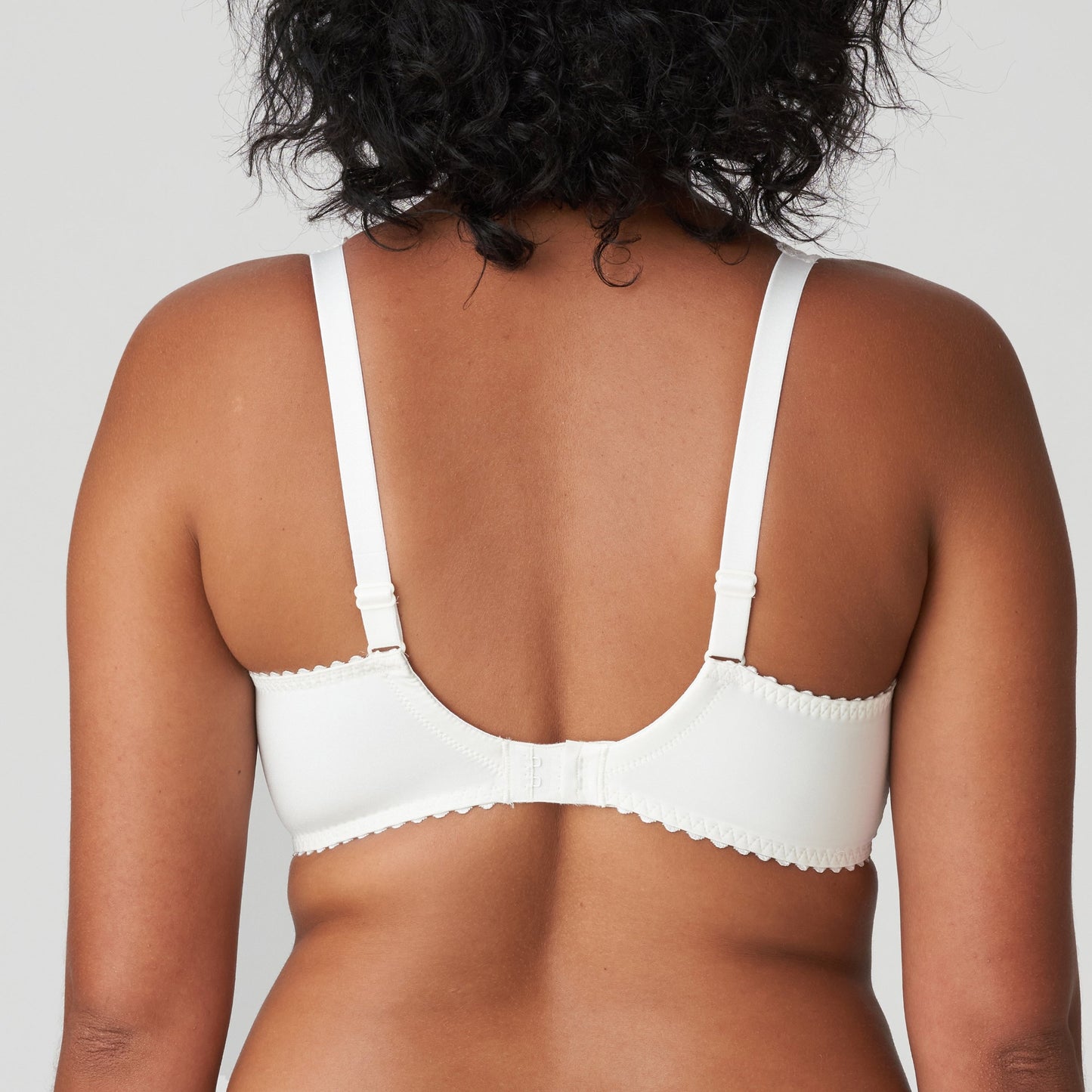 Back view of a woman wearing a white lace DD+ bra with plunge neckline by Primadonna.