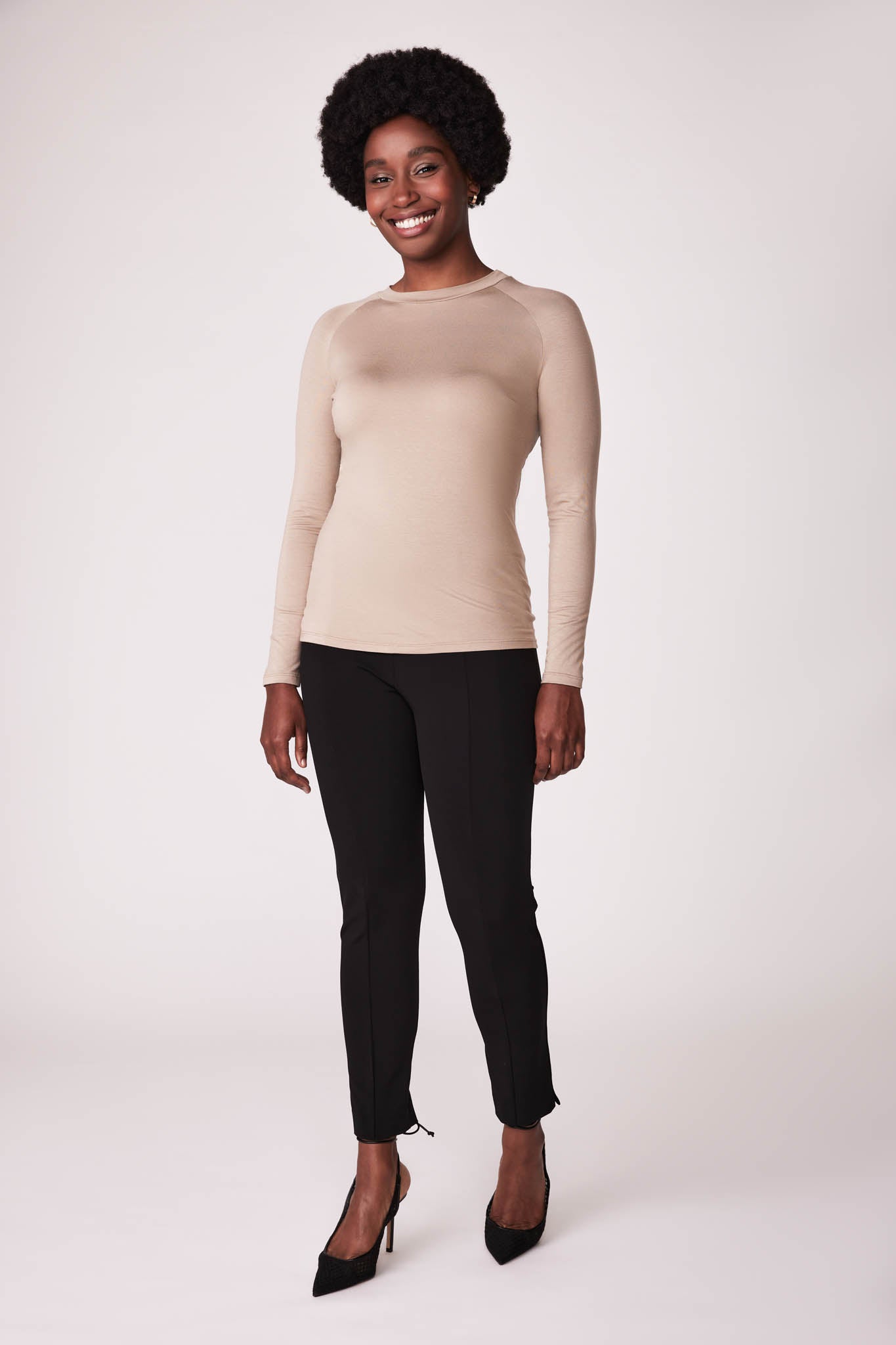 Front view of a woman wearing a beige bamboo crew neck raglan sleeve fuller bust pullover designed by Miriam Baker.