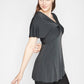Side view of a woman wearing a fuller bust low cut v-neck top with a butterfly twist detail at the empire waist in grey stretch viscose jersey by Miriam Baker.