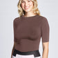 Woman wearing a fitted viscose crew neck fuller bust half sleeve T-shirt, tucked in front view of the Aarti Shirt in Quartz by Miriam Baker.