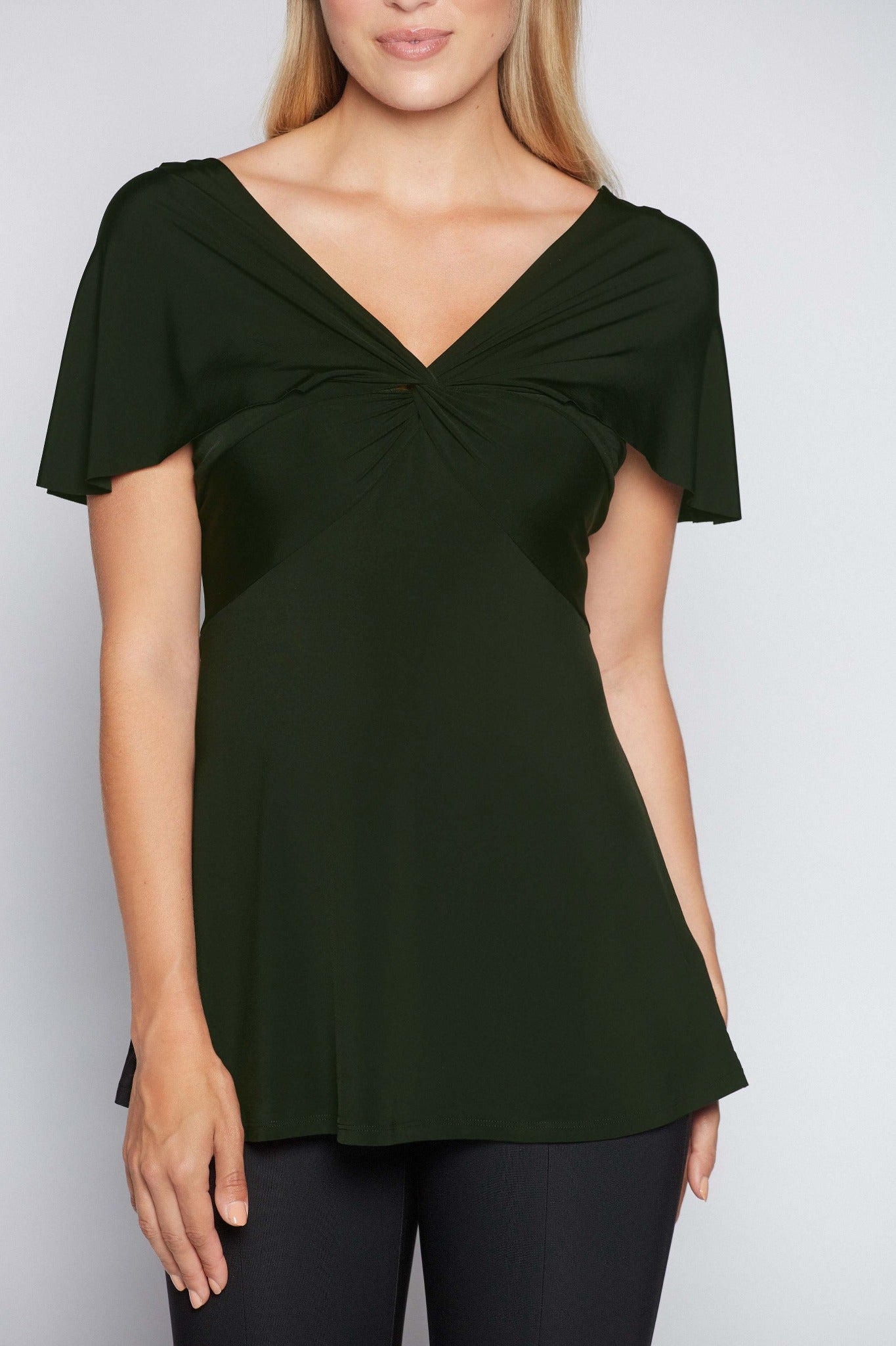 Woman wearing a fuller bust low cut v-neck top with a butterfly twist detail at the empire waist in bottle green stretch viscose jersey by Miriam Baker.