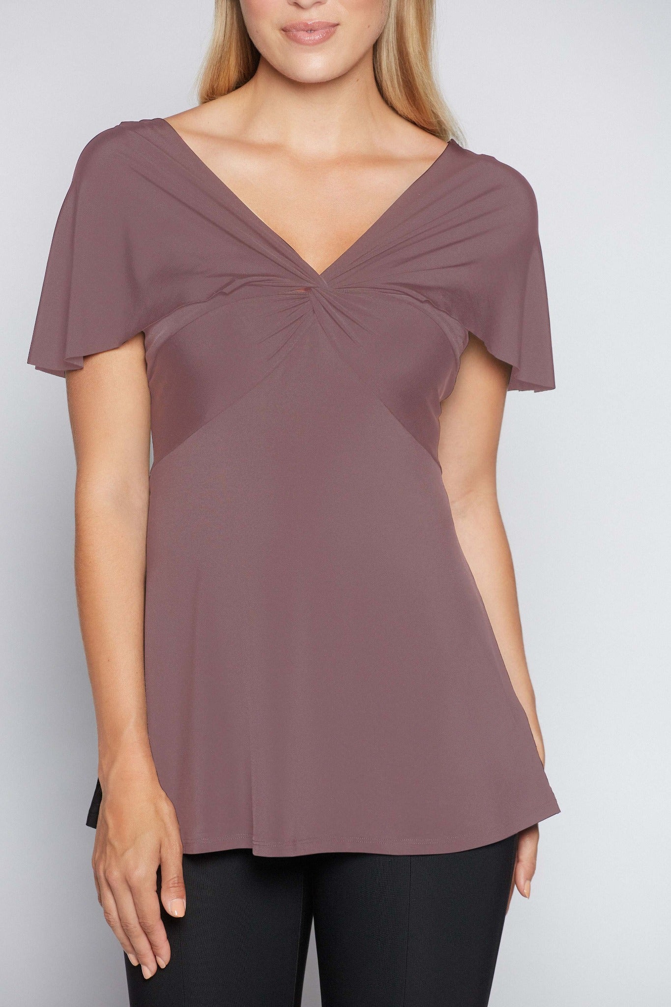 Woman wearing a fuller bust low cut v-neck top with a butterfly twist detail at the empire waist in quartz stretch viscose jersey by Miriam Baker.